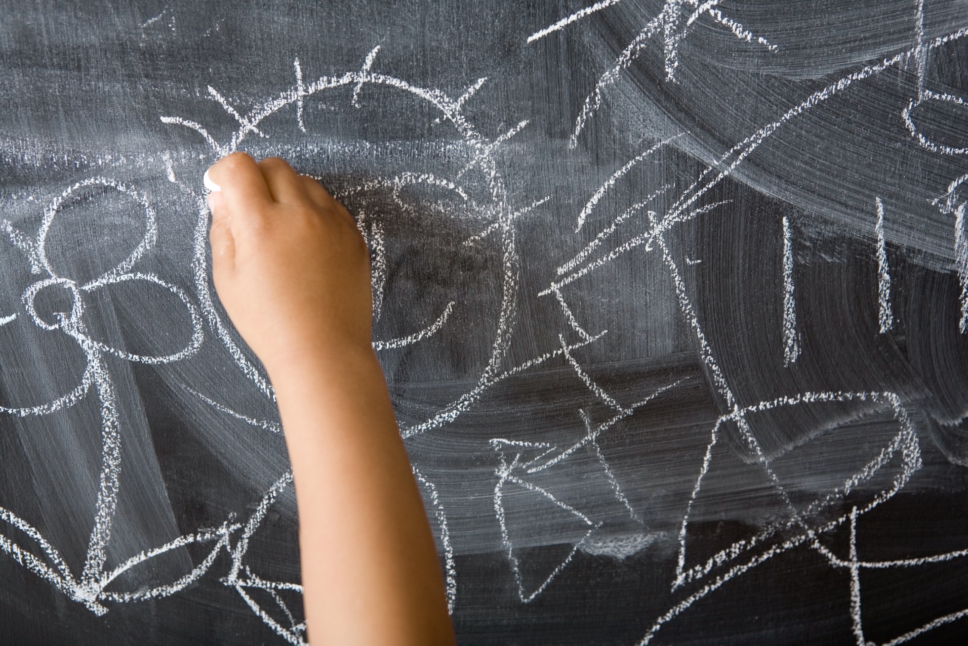 Kinderhand, die mit Kreide auf eine Tafel zeichnet